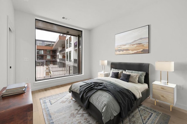 bedroom with baseboards, visible vents, and wood finished floors