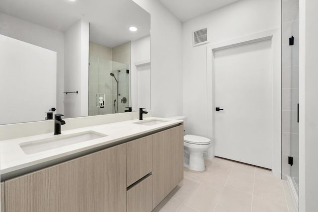 bathroom featuring a sink, a stall shower, toilet, and double vanity