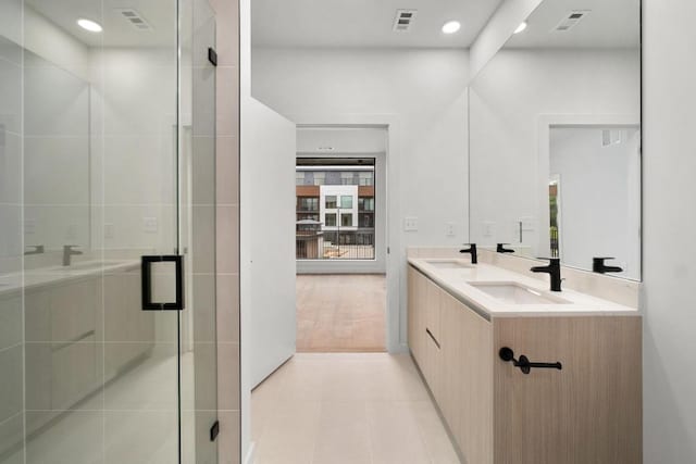 bathroom with double vanity, a sink, a stall shower, and tile patterned floors