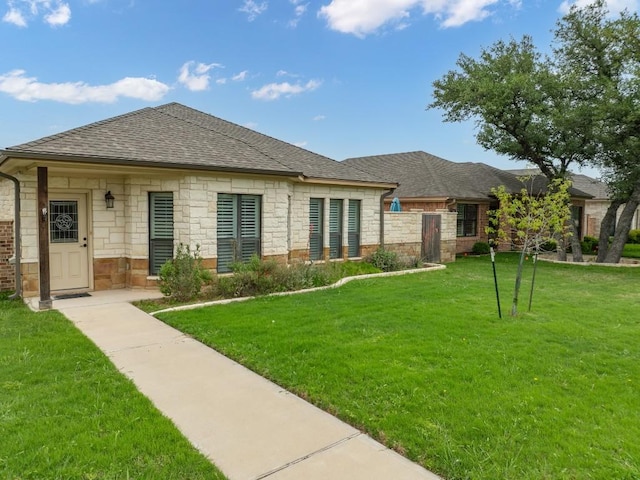 rear view of property featuring roof with shingles, a yard, and stone siding