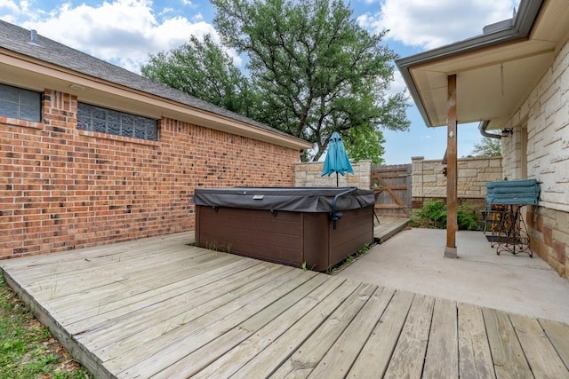 deck featuring a hot tub, a patio, and fence