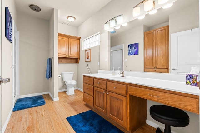 bathroom featuring vanity, toilet, baseboards, wood finished floors, and a stall shower