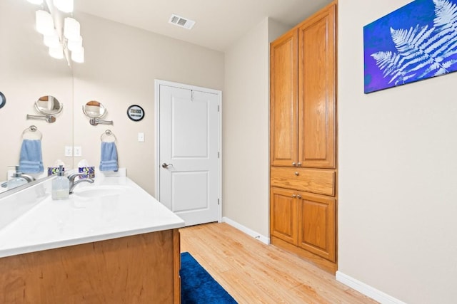 bathroom featuring vanity, baseboards, wood finished floors, and visible vents