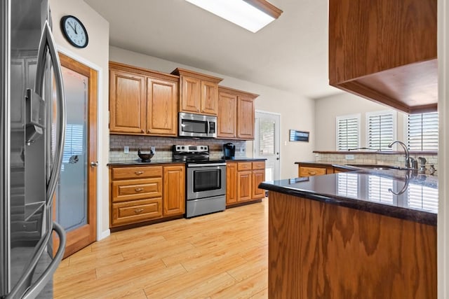 kitchen featuring stainless steel appliances, dark countertops, decorative backsplash, and a sink