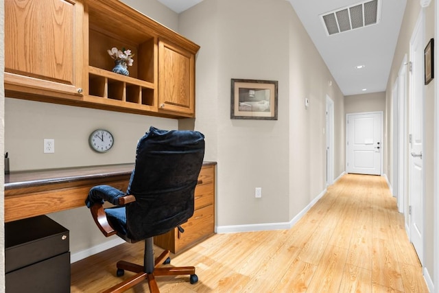 office space with baseboards, visible vents, built in desk, and light wood finished floors