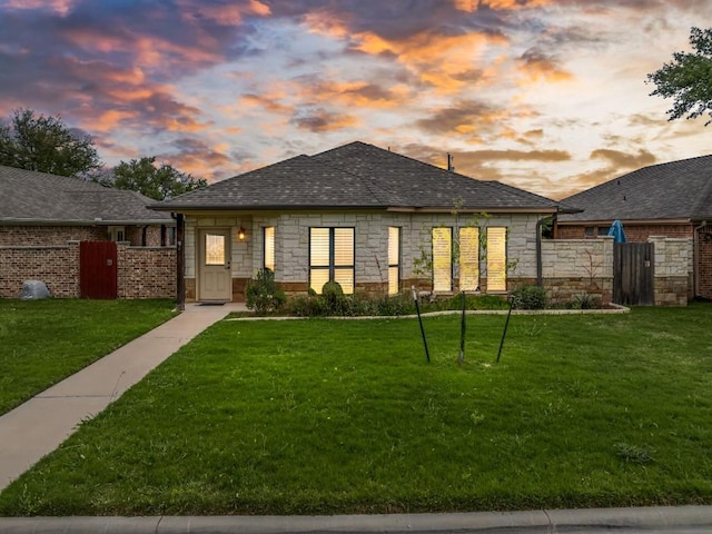 view of front of home with fence, a yard, and stone siding