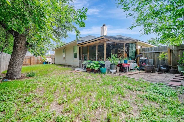 rear view of property featuring a fenced backyard, a patio area, a yard, and a chimney