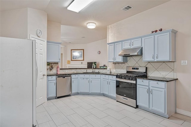 kitchen featuring appliances with stainless steel finishes, a sink, decorative backsplash, under cabinet range hood, and visible vents