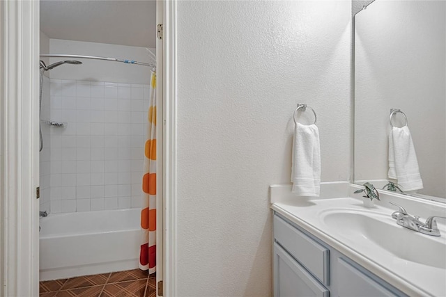 full bathroom featuring vanity, a textured wall, and shower / bath combination with curtain