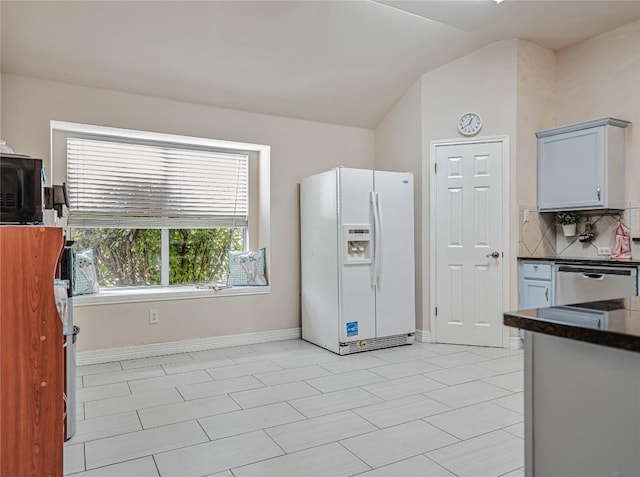 kitchen with dark countertops, dishwasher, baseboards, backsplash, and white fridge with ice dispenser