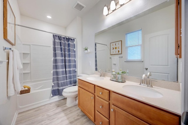 bathroom with a sink, wood finished floors, shower / tub combo with curtain, and toilet