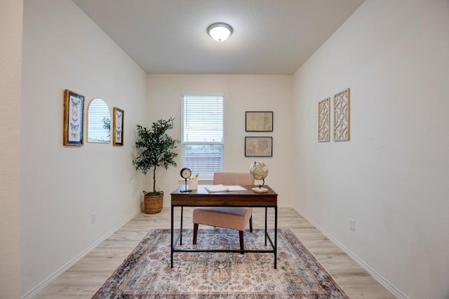 office space featuring baseboards and light wood finished floors