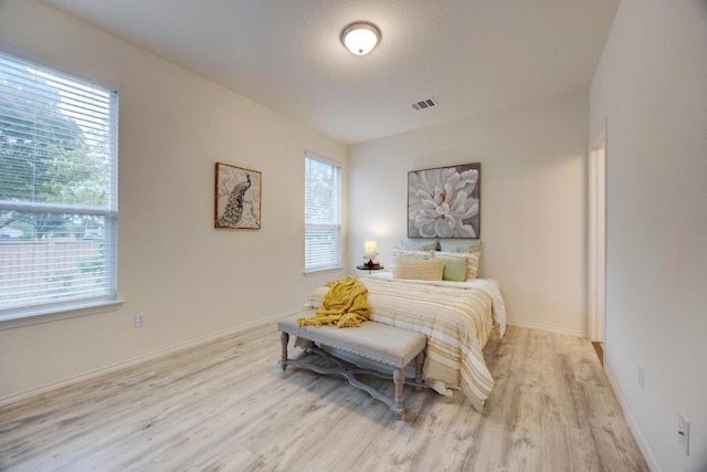 bedroom with baseboards, visible vents, multiple windows, and wood finished floors