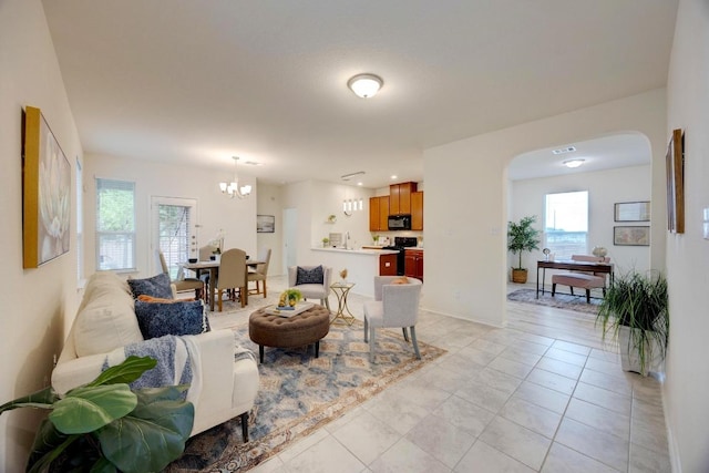 living area with arched walkways, light tile patterned floors, and a chandelier