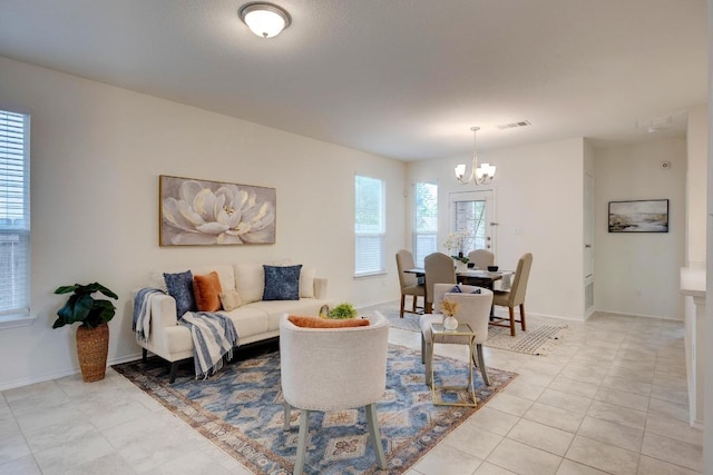 living room featuring light tile patterned floors, baseboards, visible vents, and a notable chandelier