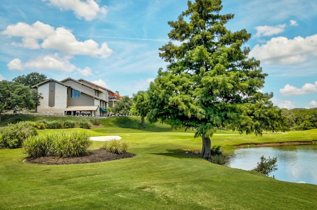 view of community with a water view, view of golf course, and a yard