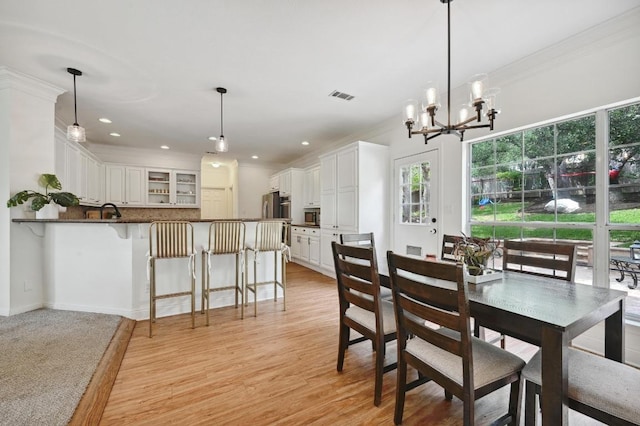 dining area with an inviting chandelier, a wealth of natural light, ornamental molding, and visible vents