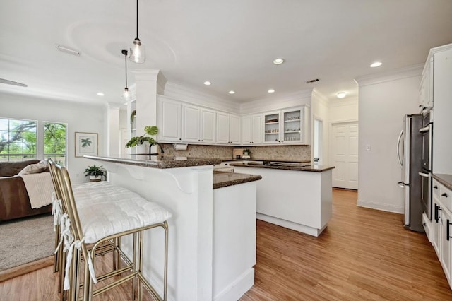 kitchen with decorative backsplash, crown molding, a peninsula, glass insert cabinets, and white cabinetry