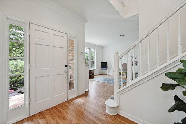 foyer entrance with baseboards, light wood finished floors, and stairs