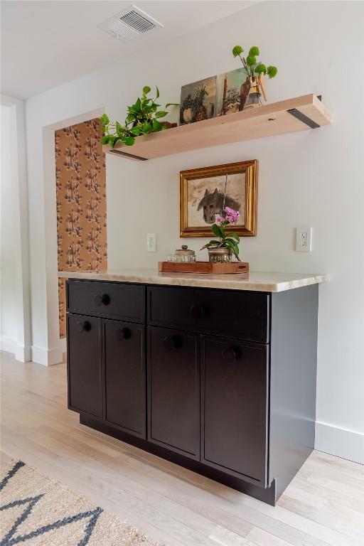 bar with visible vents, light wood-style flooring, and baseboards