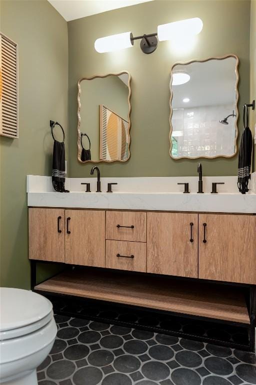 bathroom featuring double vanity, toilet, and a sink