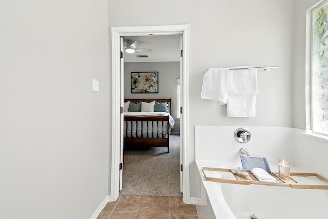 ensuite bathroom featuring a tub, a ceiling fan, visible vents, baseboards, and ensuite bath