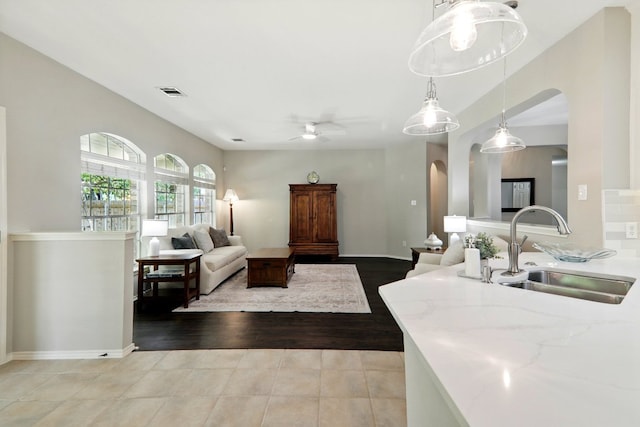 living room featuring a ceiling fan, visible vents, arched walkways, light tile patterned floors, and baseboards