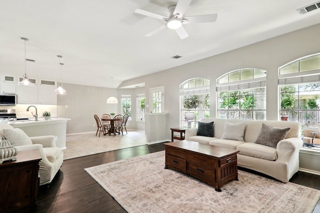 living area with visible vents, dark wood-type flooring, baseboards, and ceiling fan
