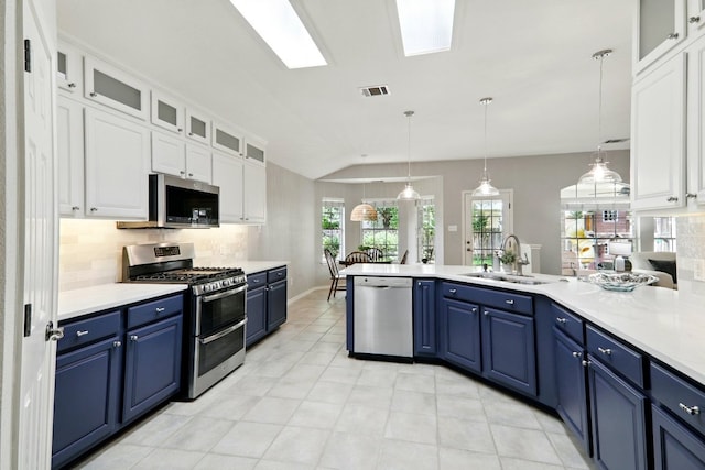 kitchen with appliances with stainless steel finishes, a sink, backsplash, visible vents, and blue cabinets