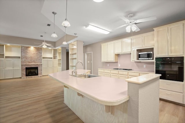 kitchen featuring ceiling fan, a sink, light wood-style floors, black oven, and stainless steel microwave