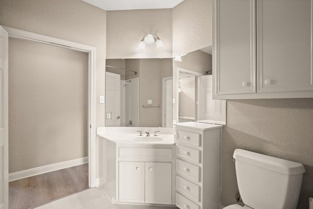 bathroom with vanity, toilet, tile patterned floors, baseboards, and a shower