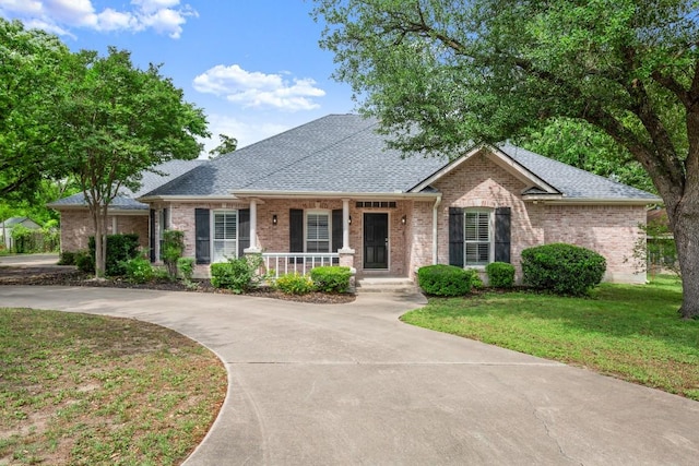 single story home with roof with shingles, covered porch, a front lawn, and brick siding