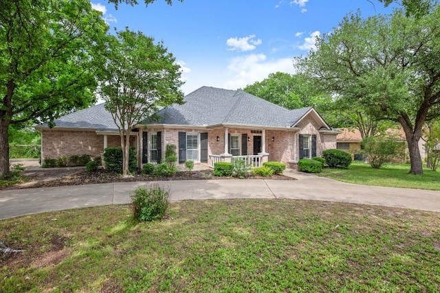 ranch-style house featuring curved driveway, a front yard, a porch, and brick siding