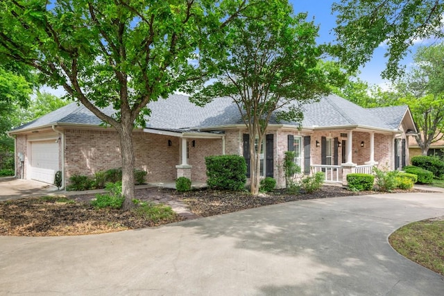 ranch-style home featuring brick siding, an attached garage, covered porch, and driveway