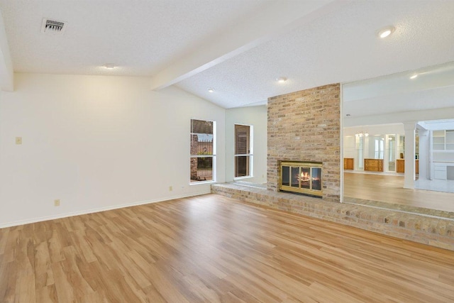unfurnished living room with visible vents, a fireplace, baseboards, vaulted ceiling with beams, and light wood finished floors