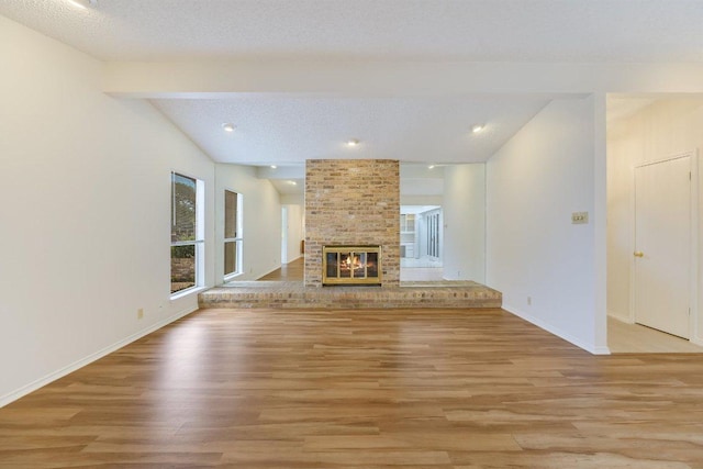 7916 Ridgeline N, Austin, TX 78731 - unfurnished living room featuring light wood finished floors, lofted ceiling, baseboards, and a brick fireplace