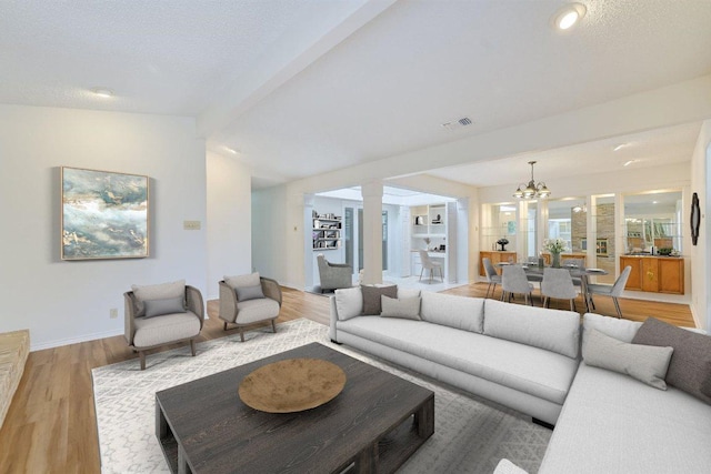 7916 Ridgeline N, Austin, TX 78731 - living room with a chandelier, light wood-style flooring, decorative columns, baseboards, and a textured ceiling