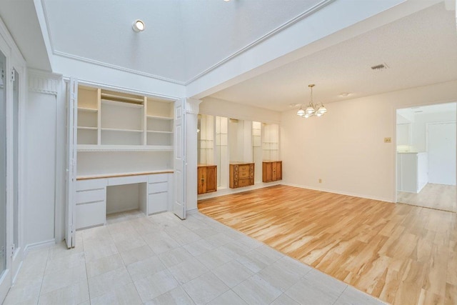 interior space with a notable chandelier, built in study area, light wood-style floors, baseboards, and visible vents