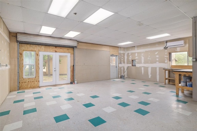 interior space featuring french doors, a wall mounted air conditioner, a drop ceiling, and tile patterned floors