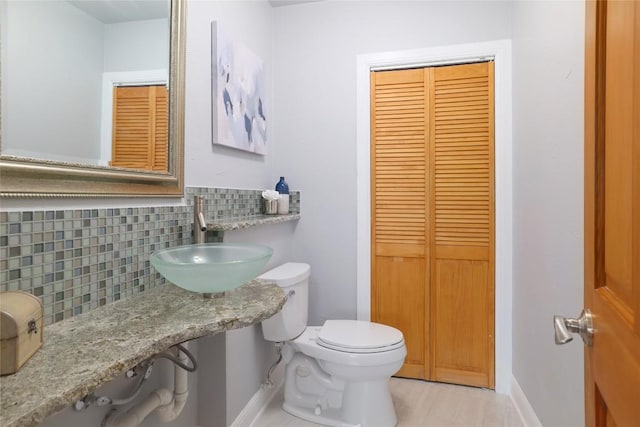 half bath featuring baseboards, a sink, and a closet