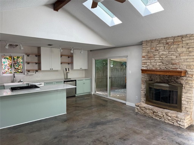 kitchen with vaulted ceiling with skylight, stainless steel dishwasher, open shelves, a sink, and cooktop