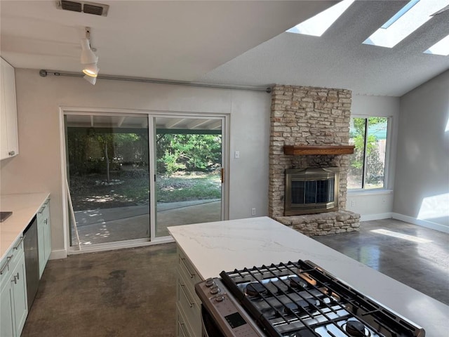 kitchen featuring baseboards, appliances with stainless steel finishes, finished concrete floors, and a fireplace
