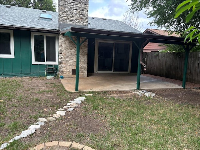 rear view of house with fence, a patio, a chimney, a shingled roof, and board and batten siding