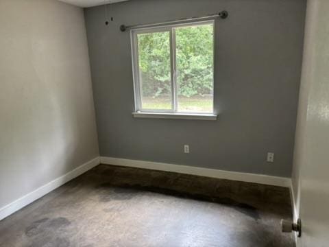 unfurnished room with baseboards and concrete floors