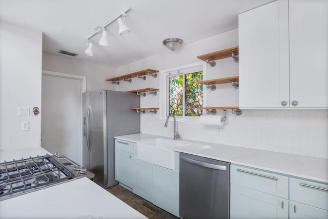 1715 Mearns Mdw, Austin, TX 78758 - kitchen with stainless steel appliances, open shelves, light countertops, decorative backsplash, and track lighting