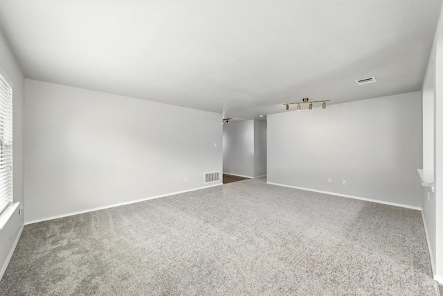 spare room featuring baseboards, visible vents, and carpet