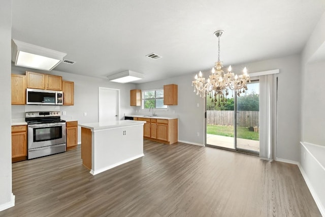 kitchen with light countertops, stainless steel appliances, a sink, and wood finished floors