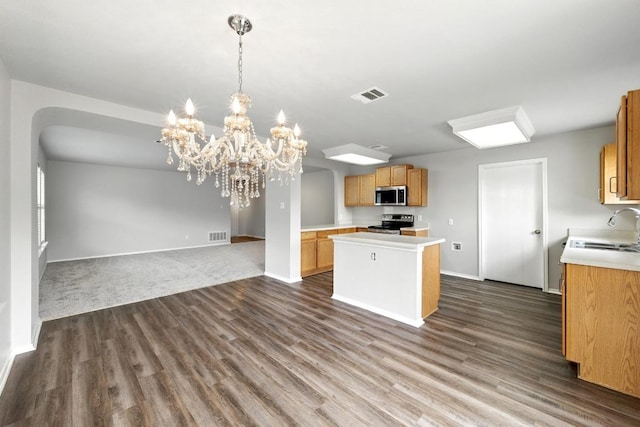 kitchen featuring a kitchen island, open floor plan, light countertops, a sink, and stainless steel appliances