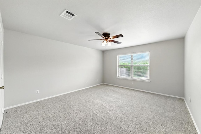 carpeted spare room featuring visible vents, a ceiling fan, and baseboards