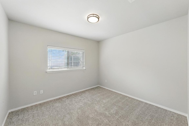 carpeted empty room featuring baseboards